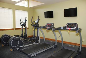 a gym with cardio equipment and a tv on the wall